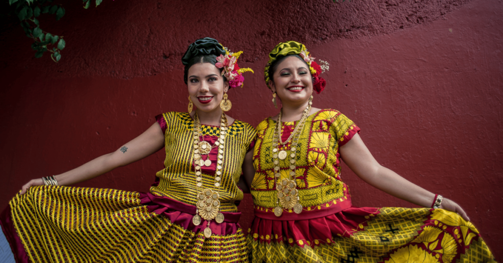 Two women dressed in typical mexican clothes smiling 