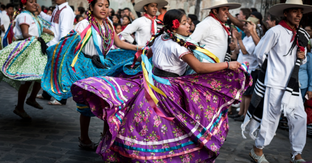 group of people dancing in costumes in the Guelaguetza celebration