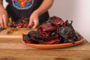 Ancho chili and guajillo chili in a clay dish on a wooden table. Chilies prepared to make red sauce.