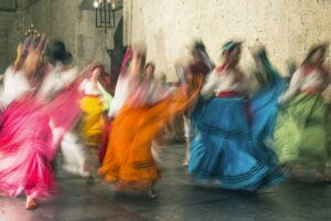 Blurred view of women dancing in traditional costumes, with bright coloured skirts